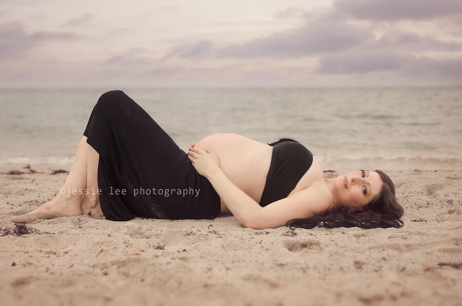 maternity photo shoot at the beach laying down looking at camera maternity photo shoot at the beach laying down looking at camera